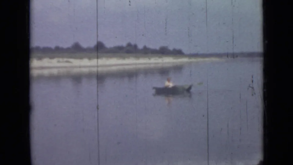 A distant person rows a small boat on calm water in this soft 1967 Saint Petersburg home-movie frame.