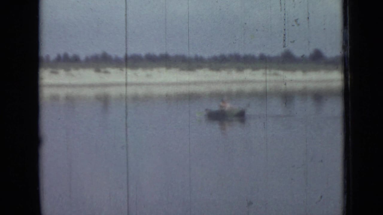 Distant person in a small rowboat crosses calm water in this soft 1967 Saint Petersburg 8mm frame.