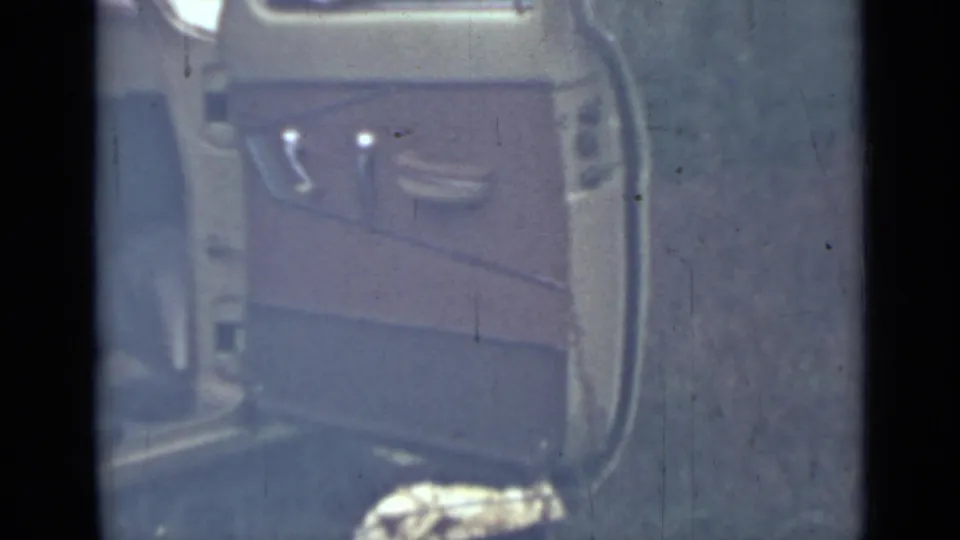 The open yellow car door fills the frame, showing the interior panel and handle against an outdoor background.
