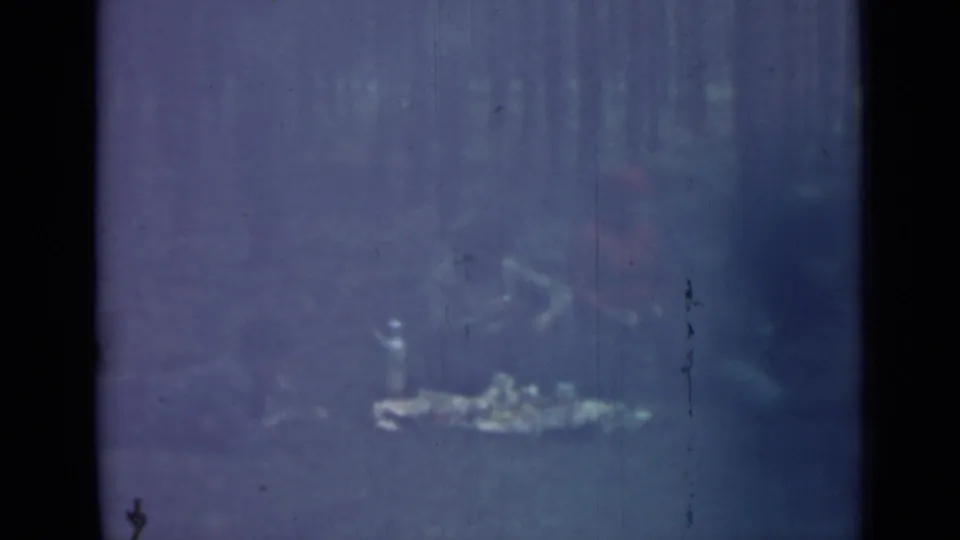 Saint Petersburg 1967 home-movie still showing a seated outdoor group and picnic items framed by dark film borders and wooded background.