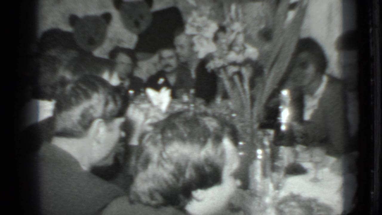 Dinner table scene viewed past several heads, with men seated in the background.