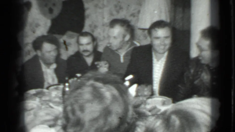 1975 Moscow dinner gathering frame with several men facing the camera across a table in a private interior.