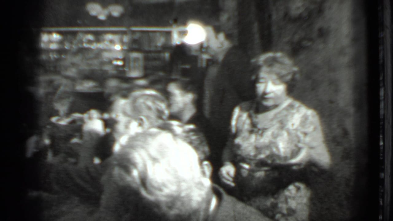 Waitress stands beside diners at a restaurant table.