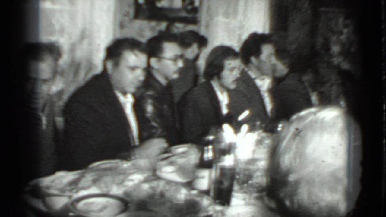 Group of adults seated at a dining table with bottles and tableware in front.