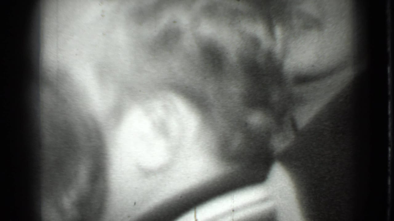 1975 Moscow 8mm frame showing a blurred close-up of a person's hair, ear, and partial face in black and white.