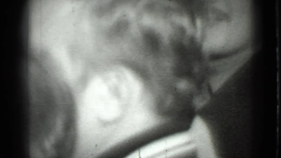 1975 Moscow 8mm frame showing a blurred close-up of a person's hair, ear, and partial face in black and white.