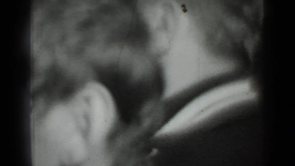 Grainy 1975 Moscow home-movie frame showing a close side view of a person's head, ear, hair, and dark coat or jacket.