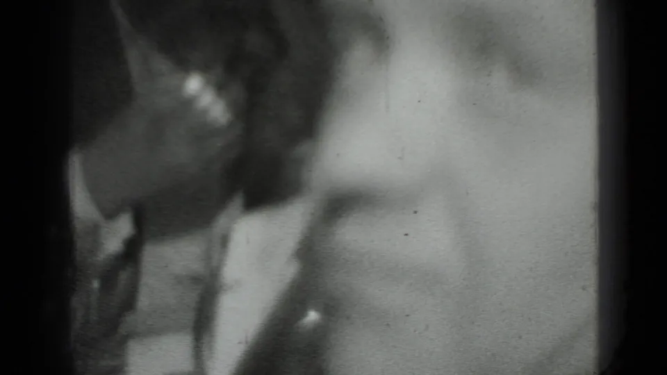 Black-and-white 8mm frame from Moscow showing part of a person's head and shoulder, with a pale soft-focus background.