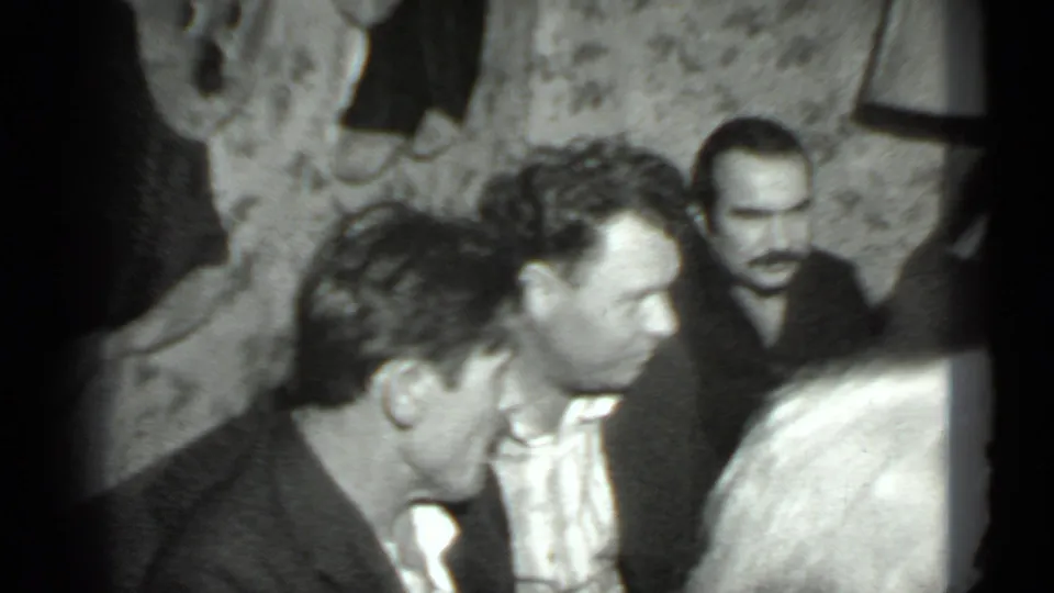 At the end of the 1975 Moscow clip, seated adults continue talking in a dim private room with patterned wallpaper.
