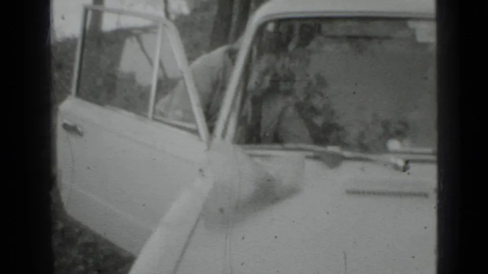 A close 1975 Moscow home-movie view shows the car's open door and a partly visible woman near the driver's side.