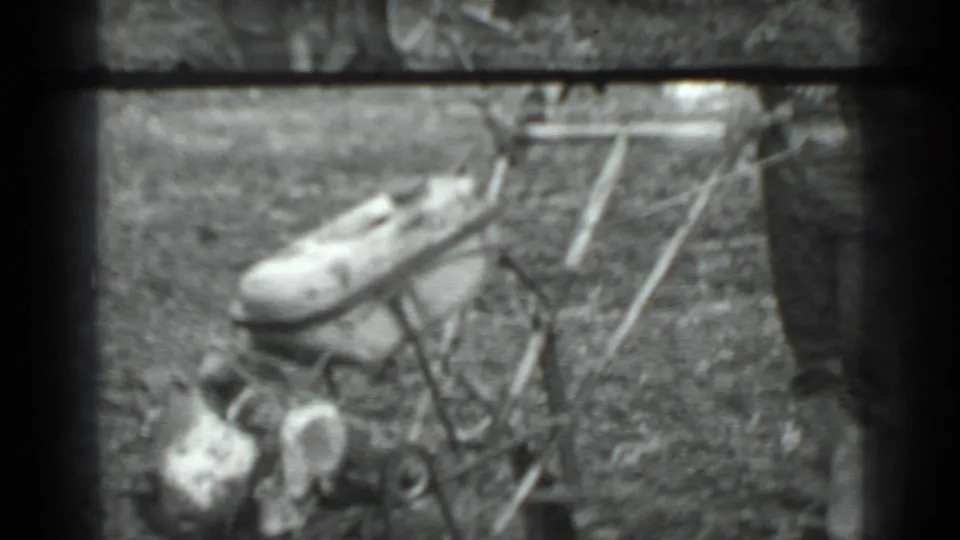 Close 8mm view of the push mower, its handle, and the operator's legs in a grassy yard.