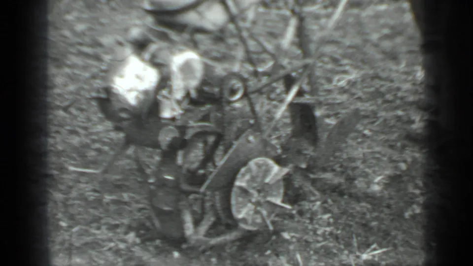 A high-angle home-movie frame shows the man and push mower on patchy ground in the Moscow yard.