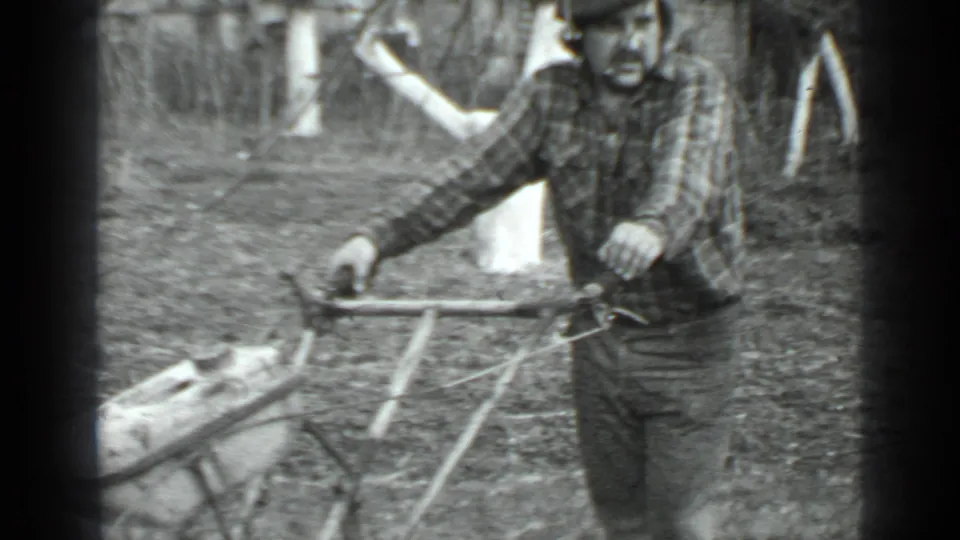 A man in plaid clothing operates or positions a wheeled grass cutter in 1975 Moscow, Russia footage.