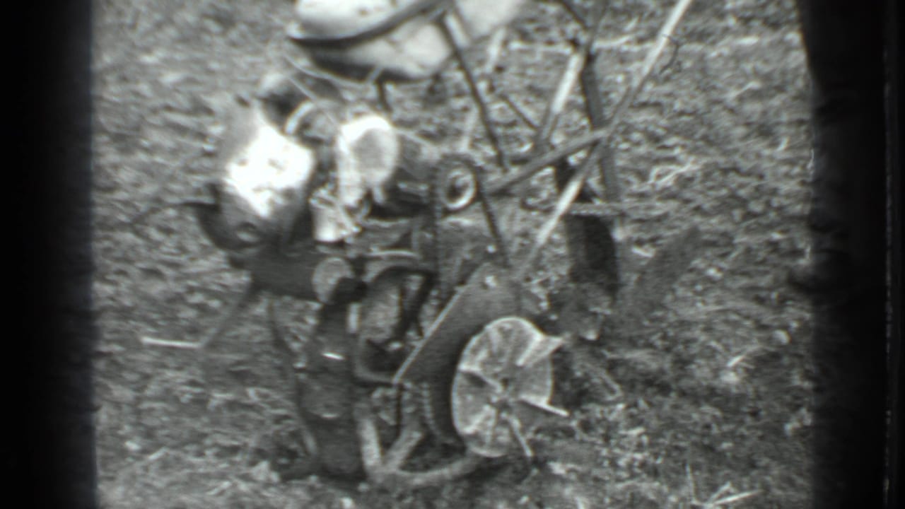 Man bends near a small motorized tiller in a rough garden plot.