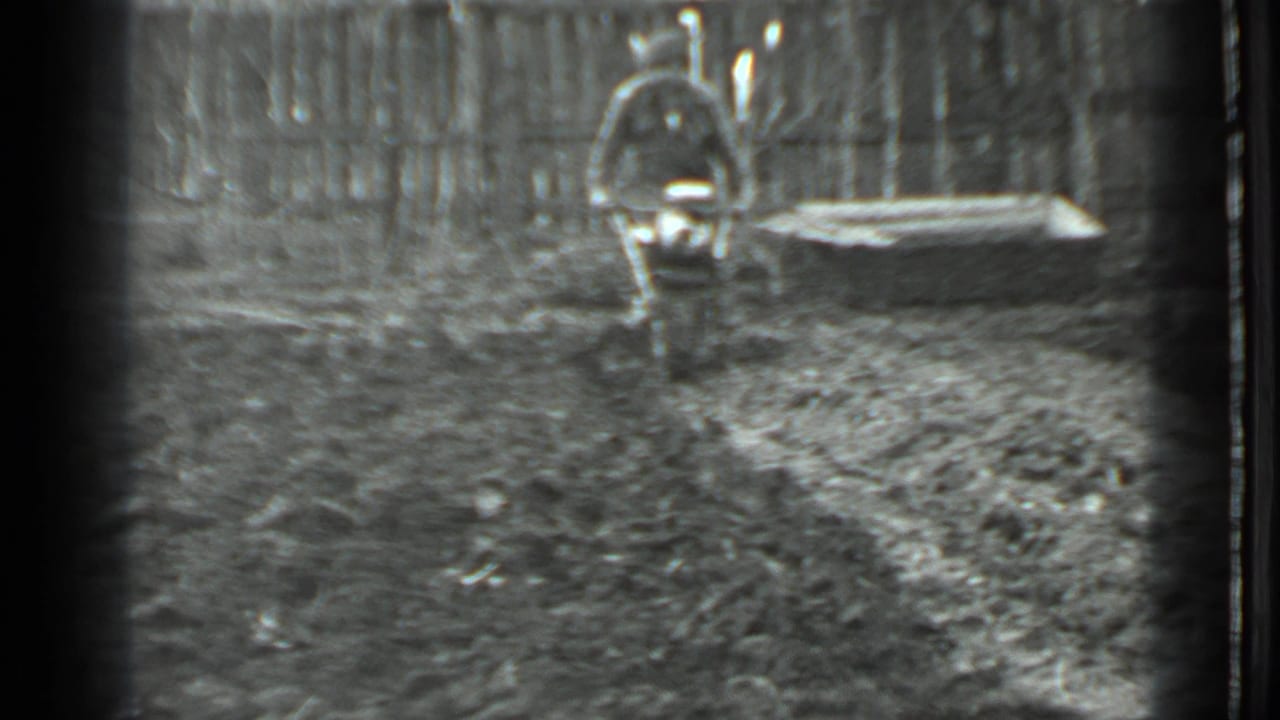 A man operates a small motorized tiller in a fenced garden yard, consistent with the supplied 1975 Moscow metadata.