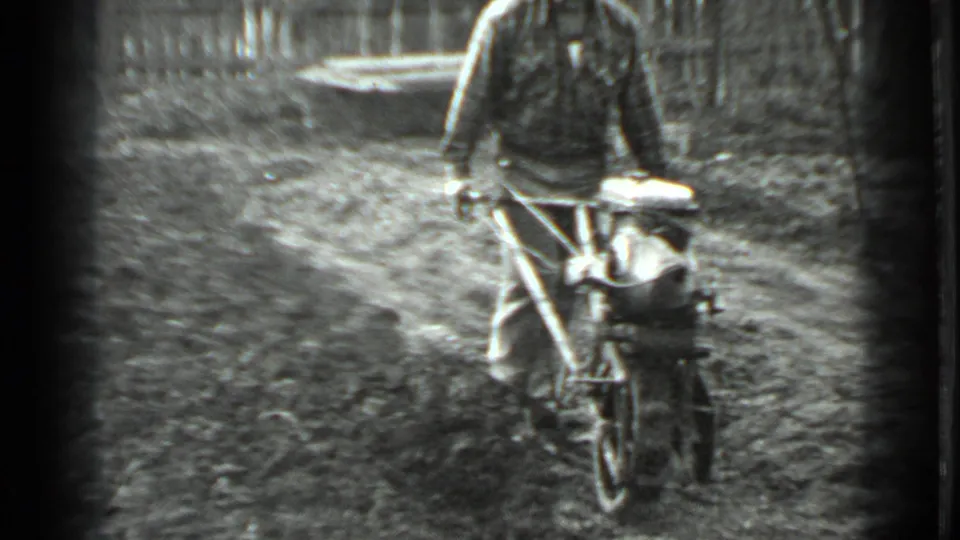 The operator advances the one-wheel cultivator through the Moscow garden plot, with rough soil and a fence visible behind him.