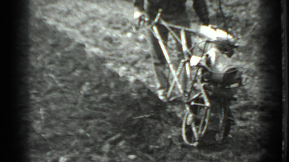 A closer 8mm frame shows the man leaning into the one-wheel tiller while it cuts through the garden soil.