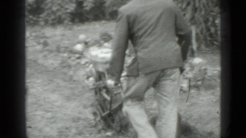 The camera follows behind as the man walks with the small tilling machine across a rough garden plot in Moscow, Russia metadata.