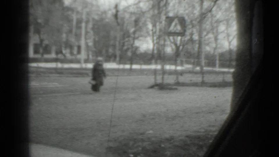 Moscow 1975 home-movie view of a woman crossing near a triangular roadside sign, seen from inside a vehicle.
