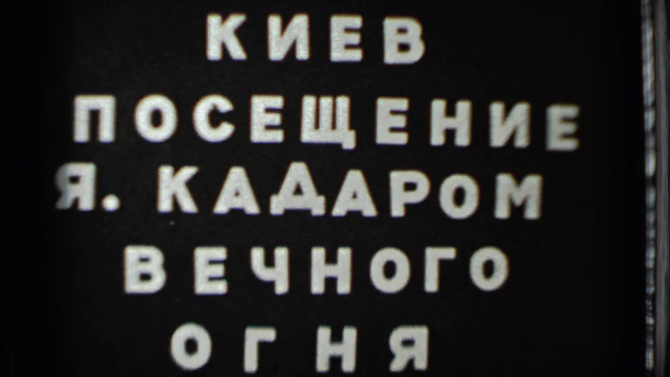 1983 8mm frame showing a black Cyrillic title card naming Kiev, J. Kadar, and the Eternal Flame.