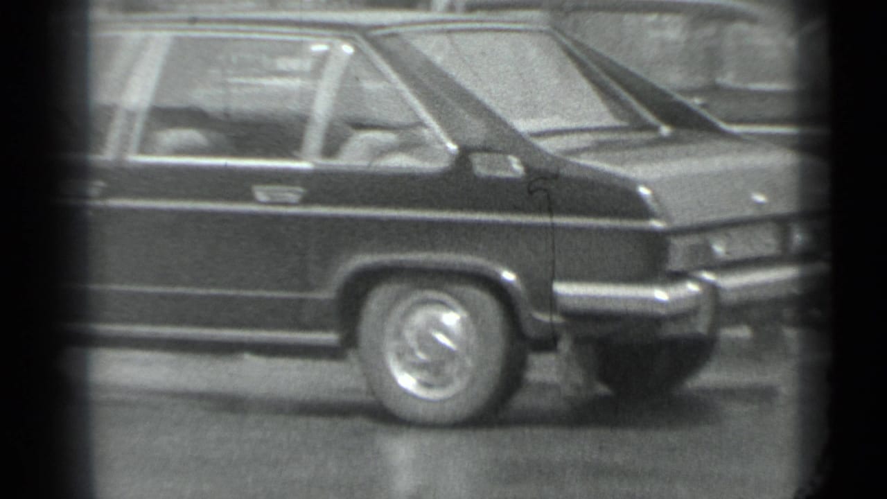 1983 Moscow 8mm frame showing the rear side of a dark stretch car with chrome trim and hubcap visible outdoors.