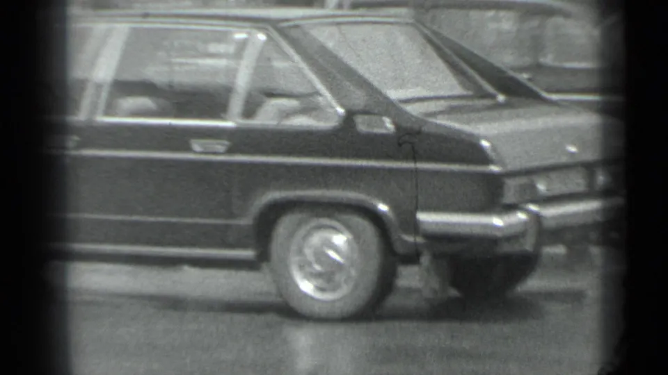 1983 Moscow 8mm frame showing the rear side of a dark stretch car with chrome trim and hubcap visible outdoors.