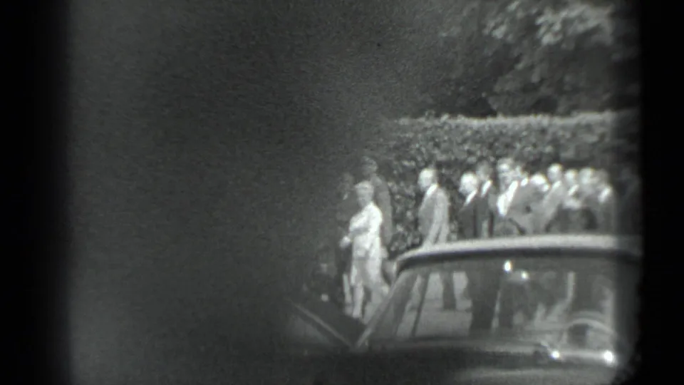 The group remains partly visible behind a parked car, with one light-clothed adult prominent against the hedge in the 1983 Moscow scene.