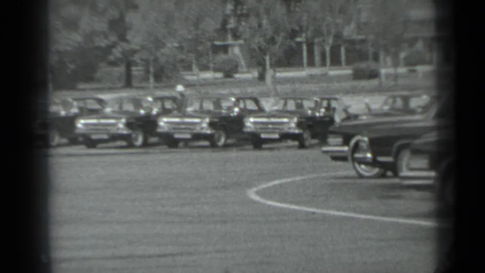 1983 Moscow street view with parked official-looking cars and motorcycle police activity seen from a distant 8mm vantage.