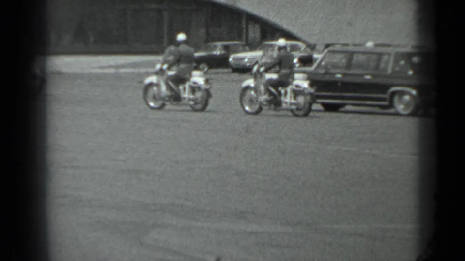 Two motorcycle officers appear to escort a dark vehicle on a Moscow street, based on the supplied 1983 clip metadata.