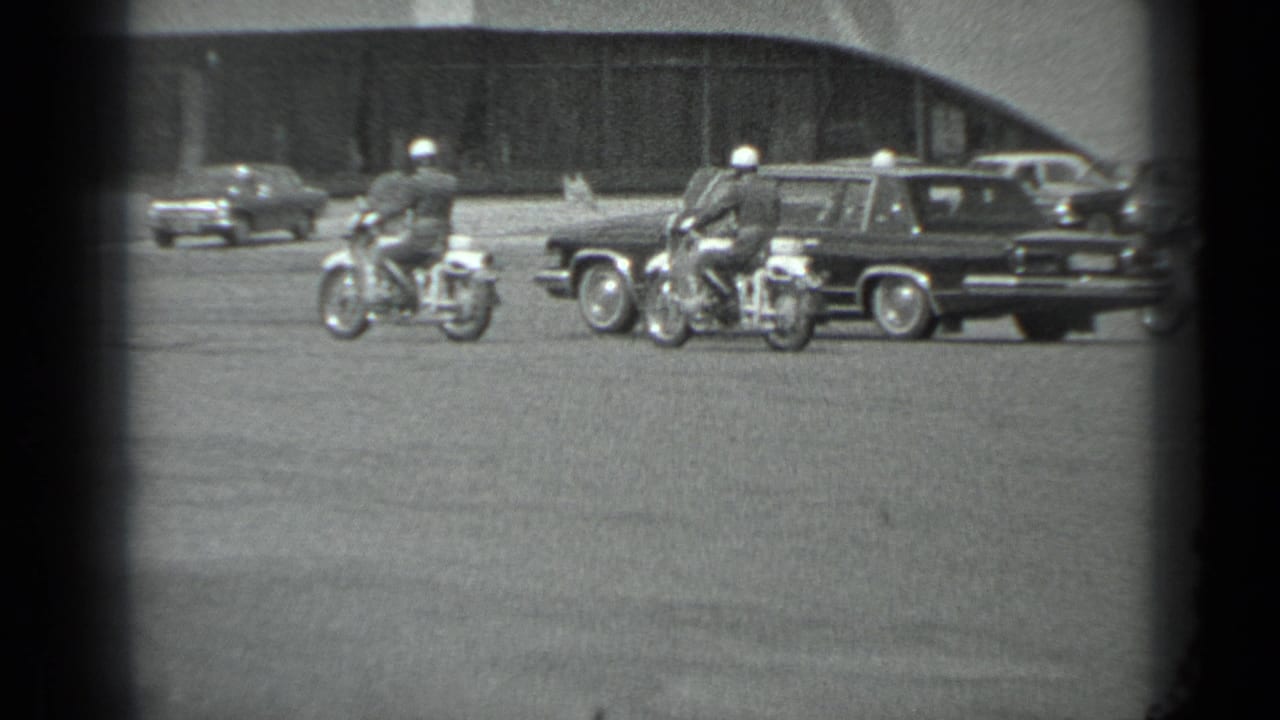 A dark sedan or limousine moves with motorcycle police nearby in a Soviet-era Moscow street scene, per supplied metadata.