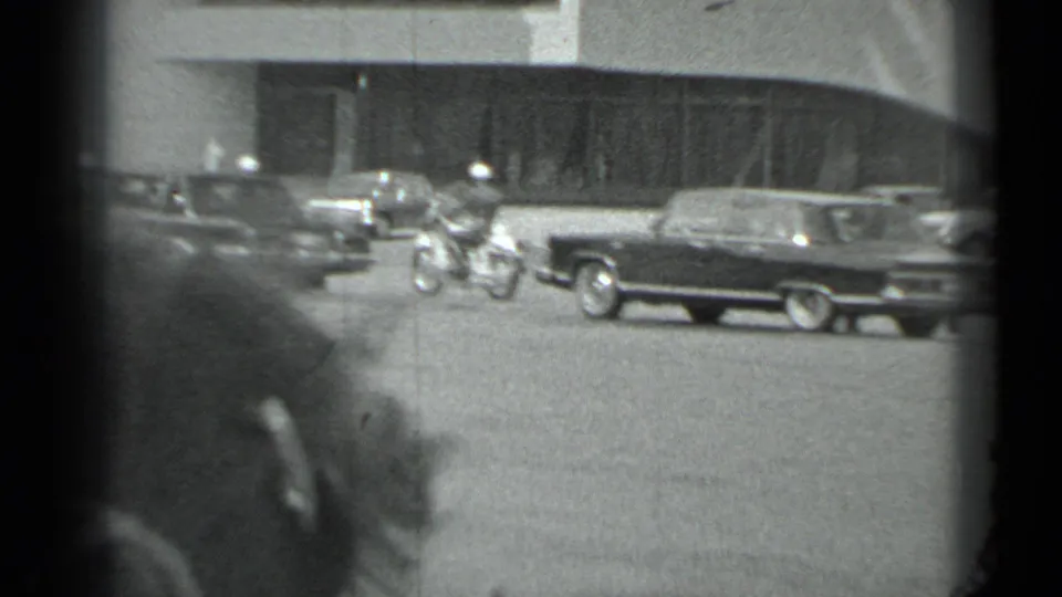 The motorcade recedes in a wider Moscow street view with several cars and a large building facade visible.