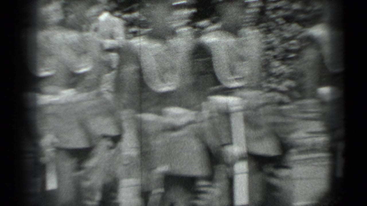 Uniformed soldiers marching beside dense hedges.