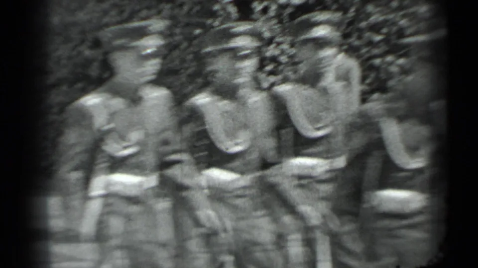 Black-and-white home-movie frame showing soldiers in uniform marching close to the camera in Moscow.