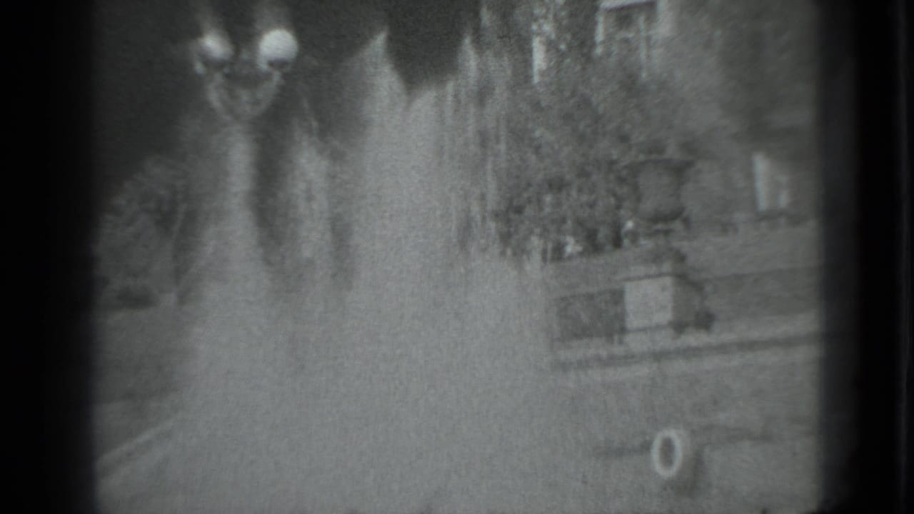 Blurred outdoor view with fountain spray, dark frame edges, and indistinct park structures.