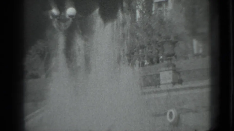 Grainy 1983 Moscow home-movie frame showing fountain spray and indistinct outdoor park details within dark 8mm frame edges.