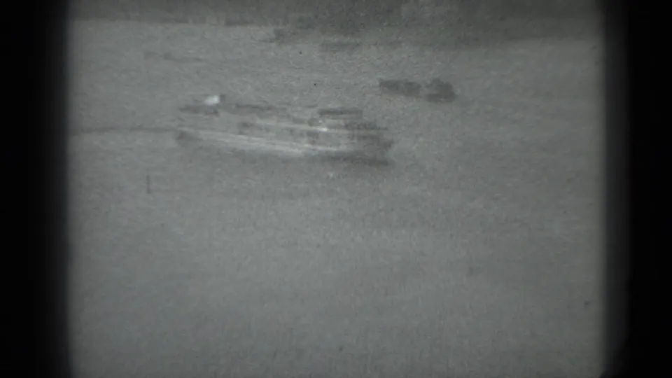 A distant ferry moves across the Moscow river in a grainy 1983 8mm frame with dark gate borders.