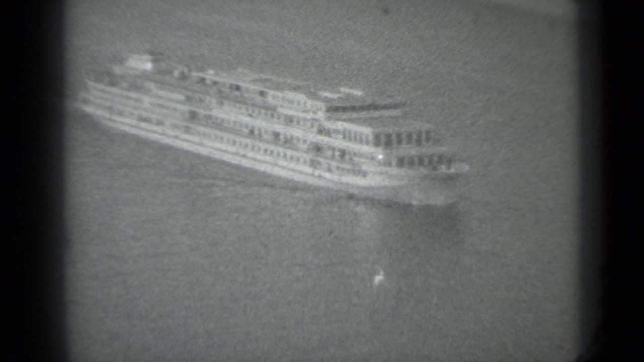 A distant passenger ship moves across water in the supplied 1983 Moscow 8mm footage, with soft focus and visible frame borders.