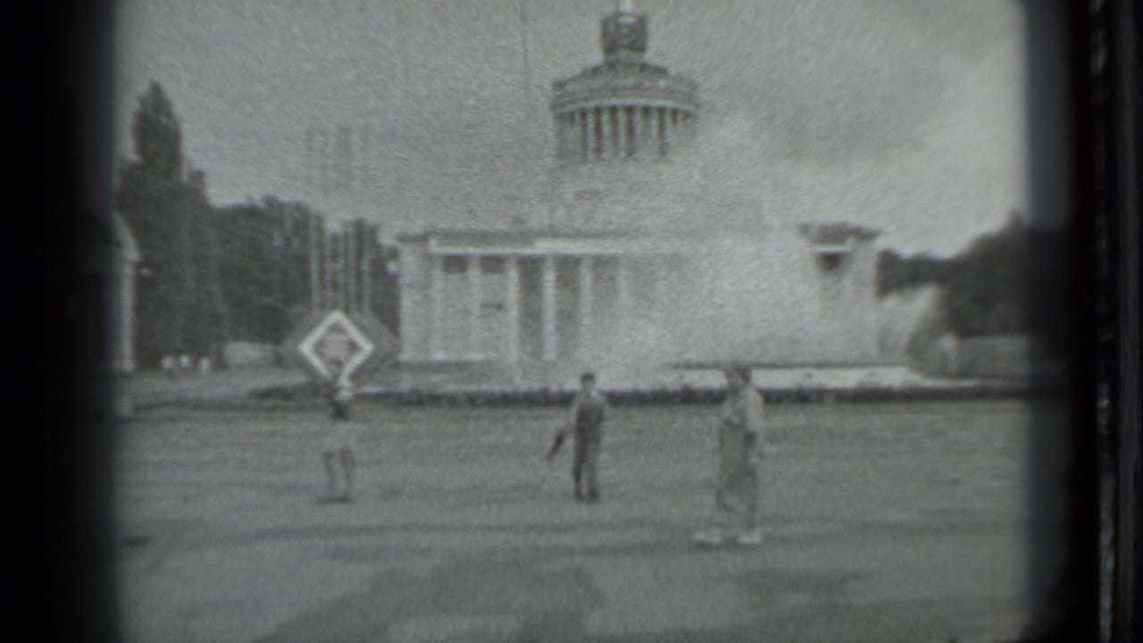 Distant people on a lawn near a domed classical building with columns.