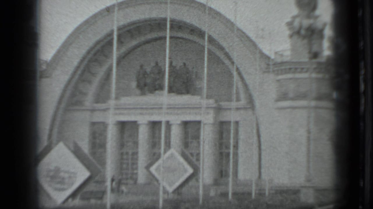 1983 Moscow 8mm frame focused on an ornate arched entrance with columns, flagpoles, sculptural figures, and diamond-shaped signs.