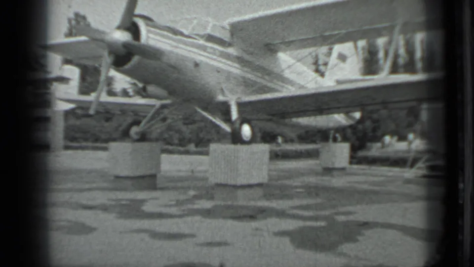 Closer 1983 Moscow airport view of the aircraft wing and landing gear, with blocks or stands on the damp tarmac.