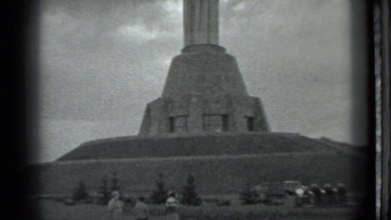 The Moscow landmark appears across a grassy slope, with visitors and parked cars small in the lower frame.