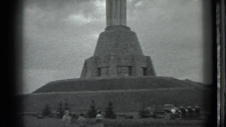The Moscow landmark appears across a grassy slope, with visitors and parked cars small in the lower frame.