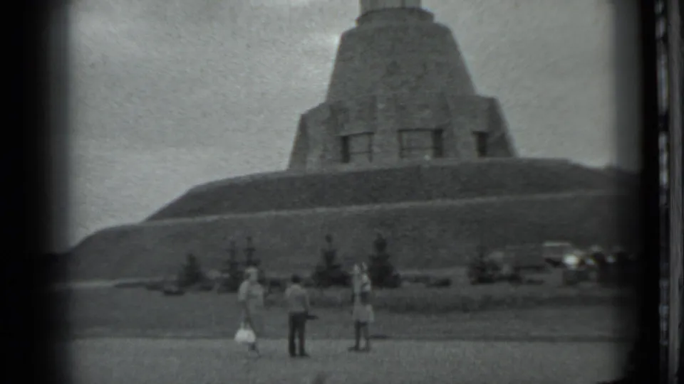 A wider 1983 Moscow home-movie frame shows several visitors at the base of the hilltop monument.