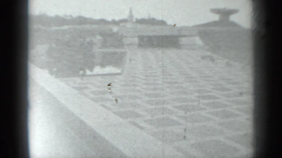 The camera looks across a patterned plaza surface toward low walls and a distant monumental form in 1983 Moscow home-movie footage.