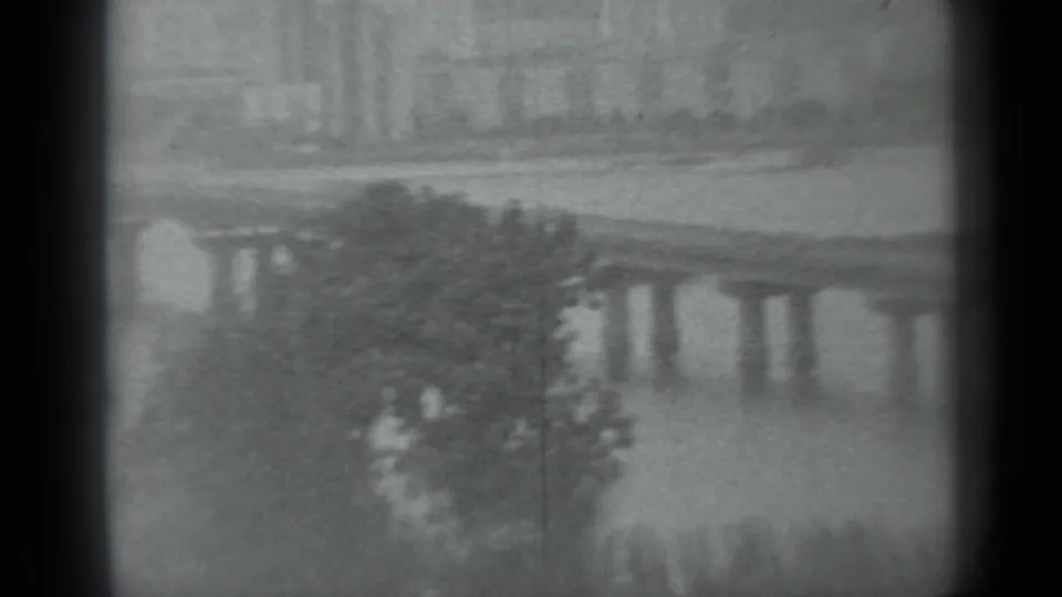 1983 Moscow home-movie frame showing a distant bridge over water, riverside trees, and soft film-gate edges.