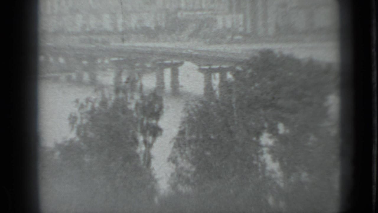 Black-and-white 8mm frame of a Moscow river bridge with trees near the water and a muted distant bank.