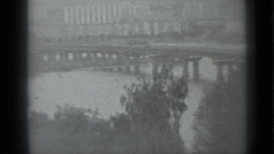 1983 Moscow frame showing a bridge over the river, foreground trees, and distant embankment shapes through soft 8mm focus.