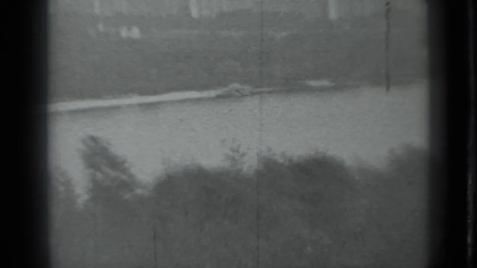 Grainy 1983 Moscow 8mm frame looking across water toward a blurred shoreline with trees and heavy film-edge borders.