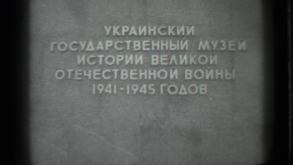 Close 8mm frame of Cyrillic museum lettering naming the Great Patriotic War years, filmed from a visitor viewpoint.