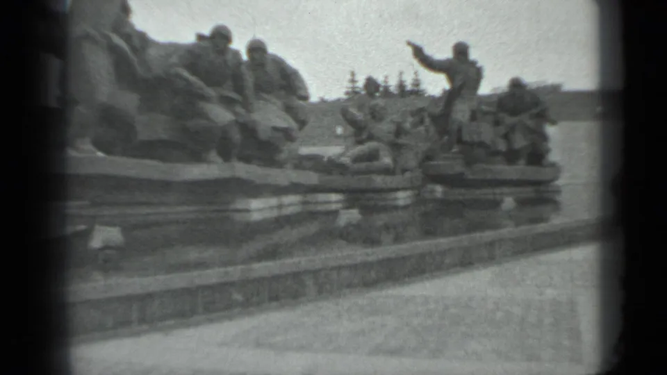 1983 visitor-shot 8mm view of a monumental Soviet-era war sculpture with soldiers, one figure raising an arm, and a paved foreground.